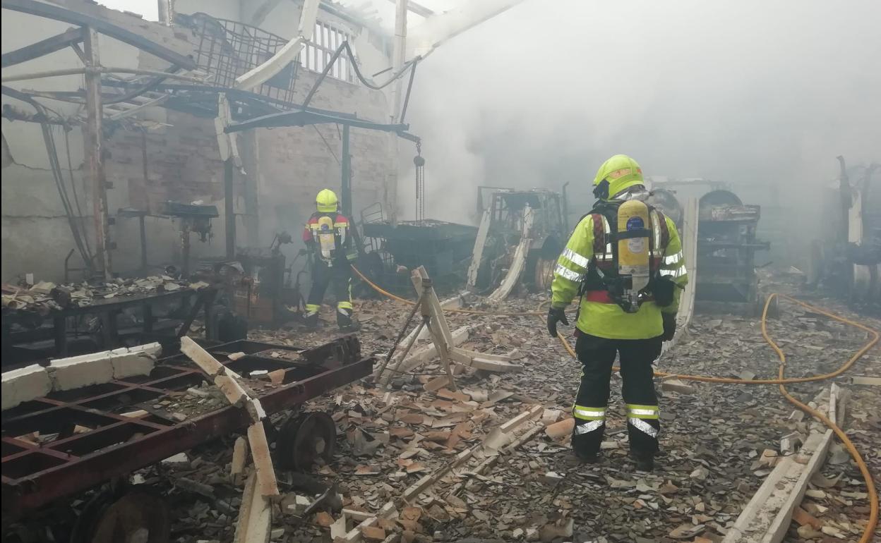 Los bomberos trabajan en el interior del pabellón. 