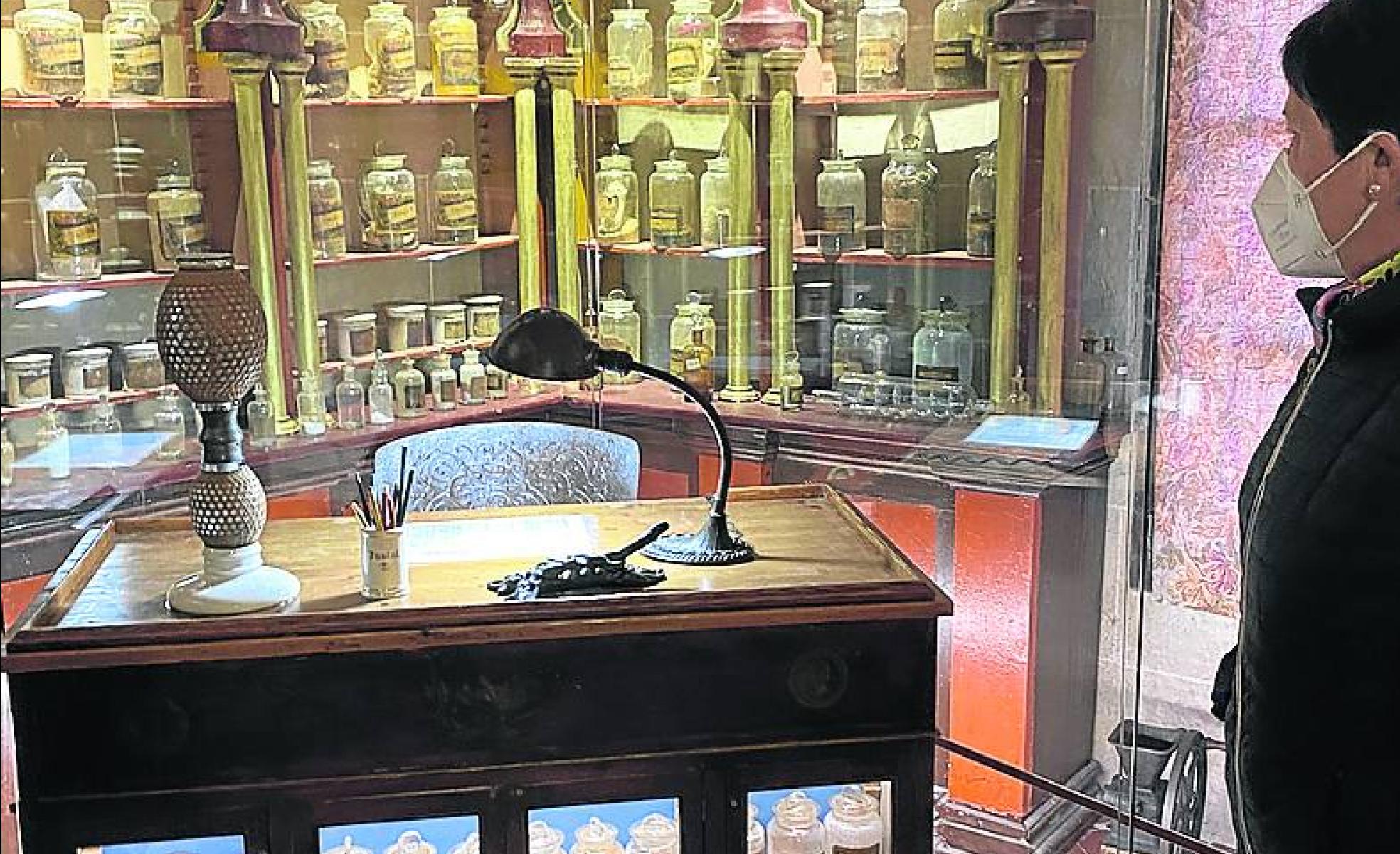 Vitrinas con remedios.Un visitante observa los botes del boticario. 