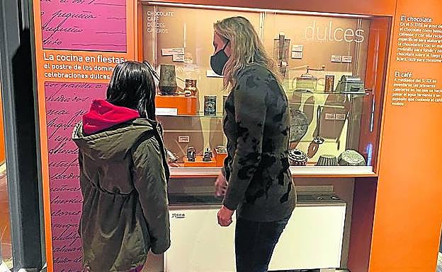 Imagen principal - Arriba, vitrinas con utensilios de cocina antiguos en la Casa Encantada. Abajo a la izquierda, una cuna y una cama de niños, en la sección de dormitorios. A la derecha, el párroco de Briones abre la puerta que oculta la sacristía. 