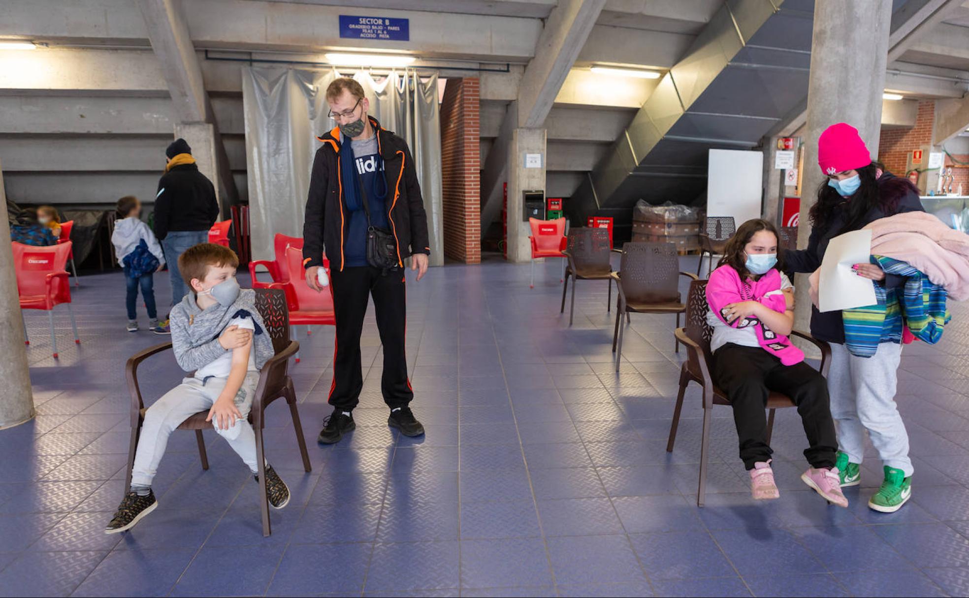 Los hermanos Javier y Daniela Álvarez Latorre, acompañados por su padres, Ricardo y Mireia, reposan sentados tras recibir su dosis. 