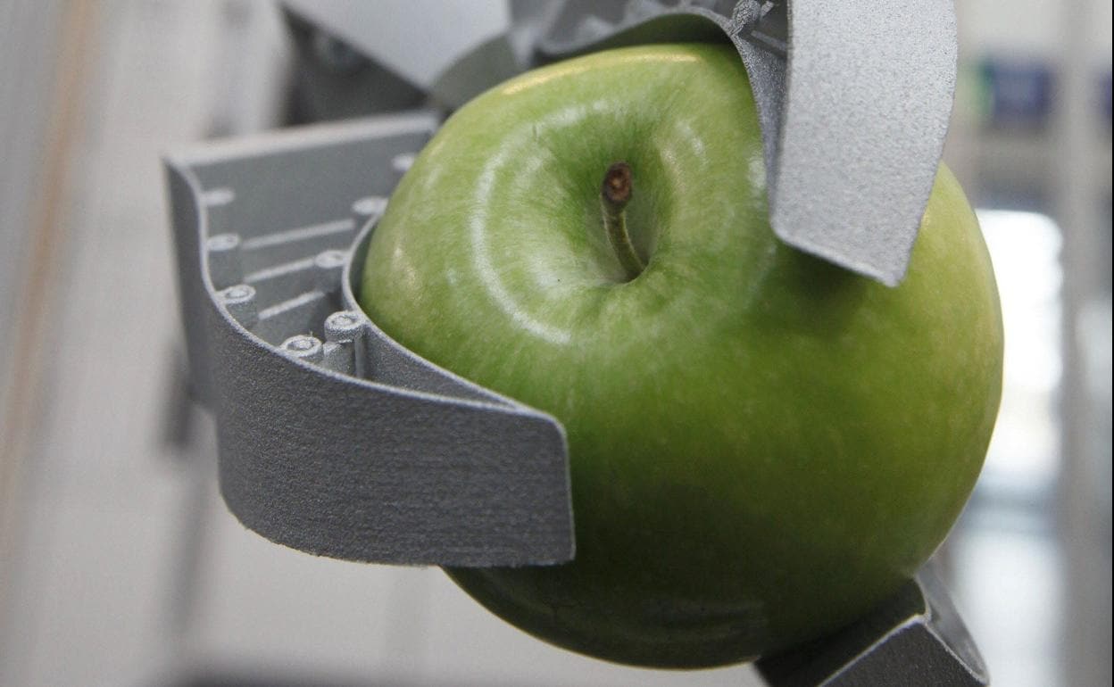 La mano de un robot biónico aferra una manzana. 