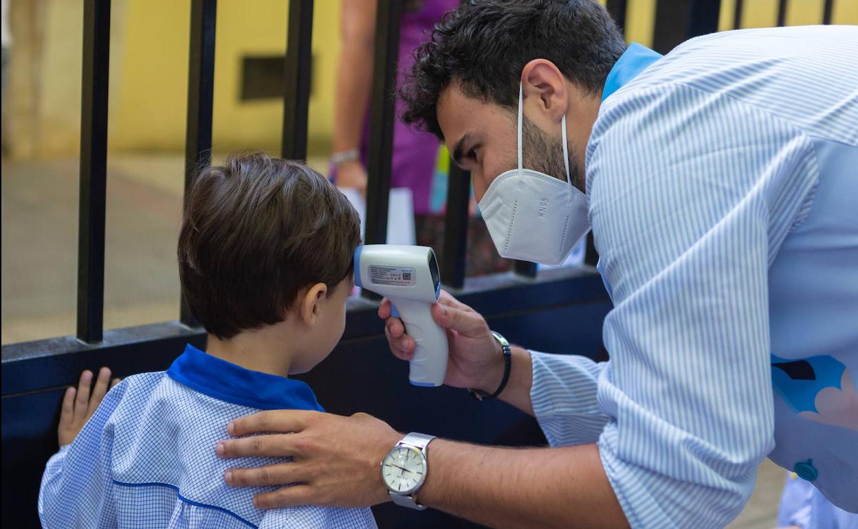 Un profesor toma la temperatura a un alumno riojano. 