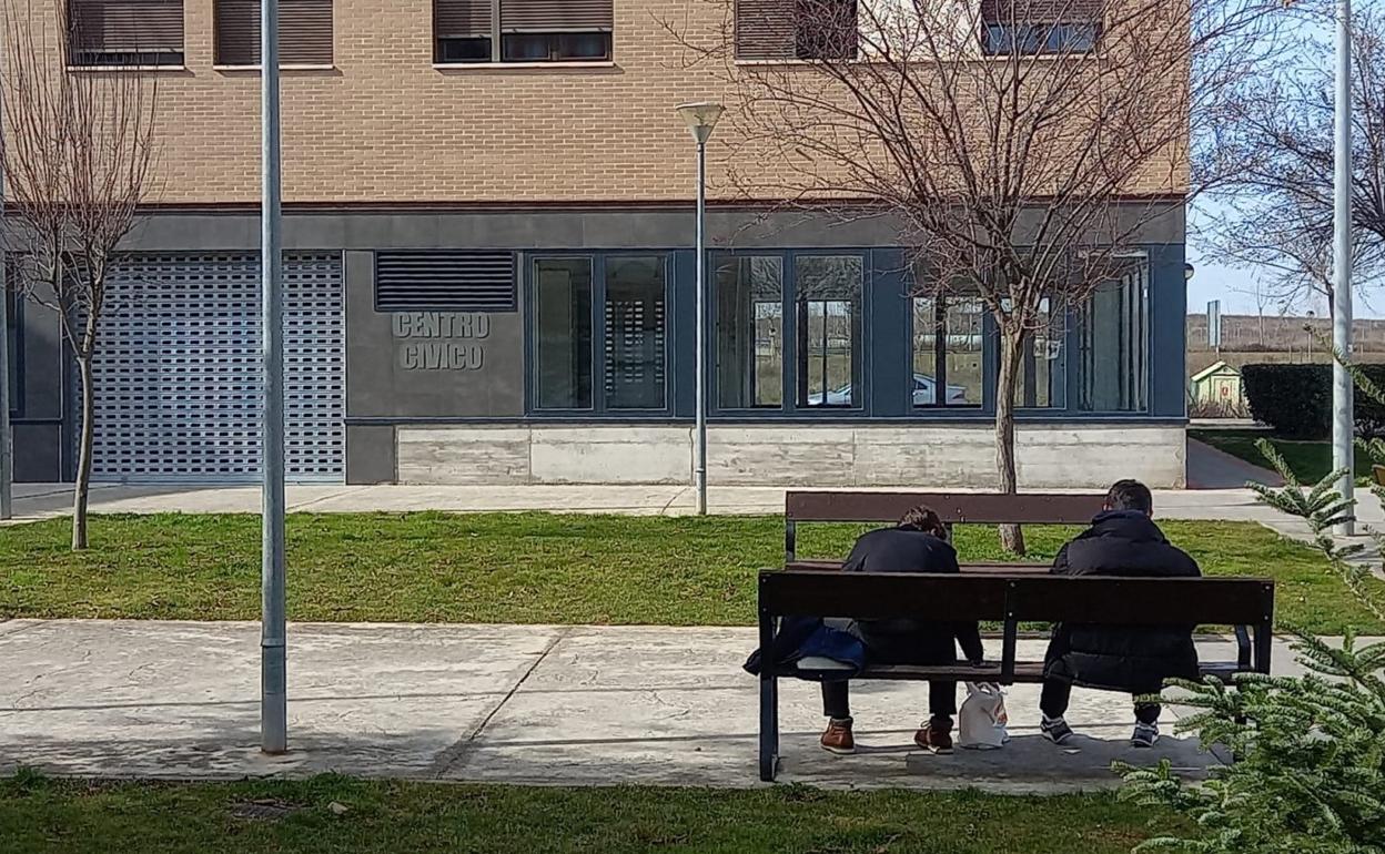 Dos jóvenes pasan el rato sentados en un banco del parque Entre Ríos frente al centro cívico cerrado. 