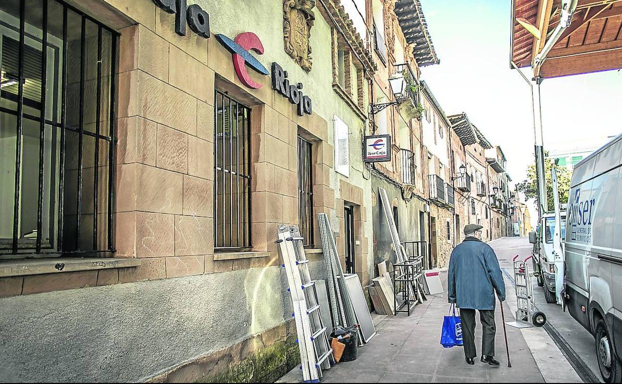 Un anciano pasa junto a la única sucursal que permaneció abierta en Tricio hasta el pasado 1 de febrero y que está siendo desmantelada. 