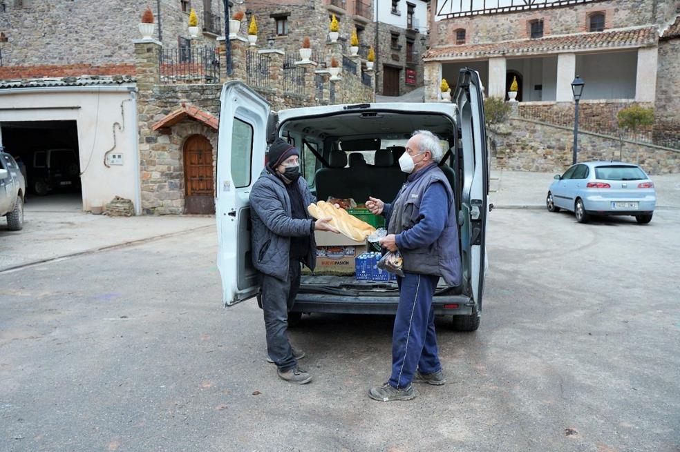 Elías López de Calle vende pan a Jaime, vecino de Ajamil, el pasado mes de febrero, en uno de sus últimos viajes. 