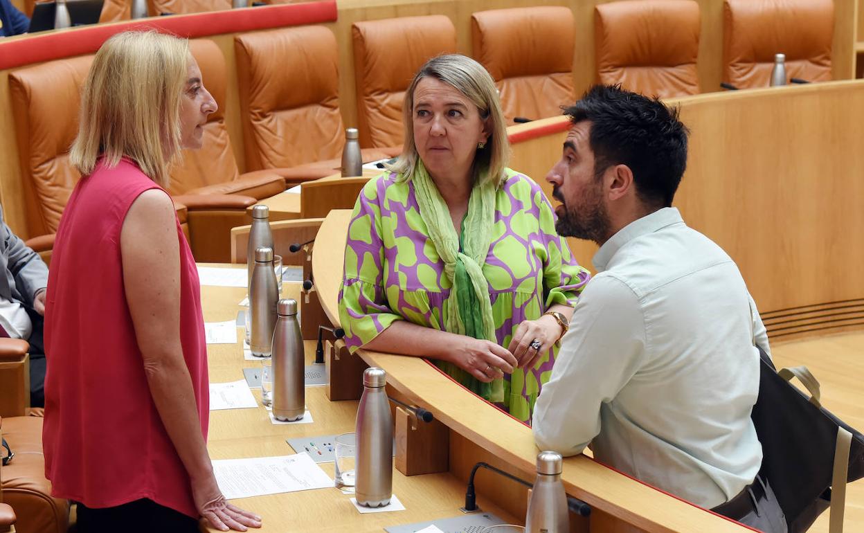 María Somalo, Eva Hita y Álex Dorado conversan momentos antes de iniciarse la sesión plenaria en el Parlamento regional. 