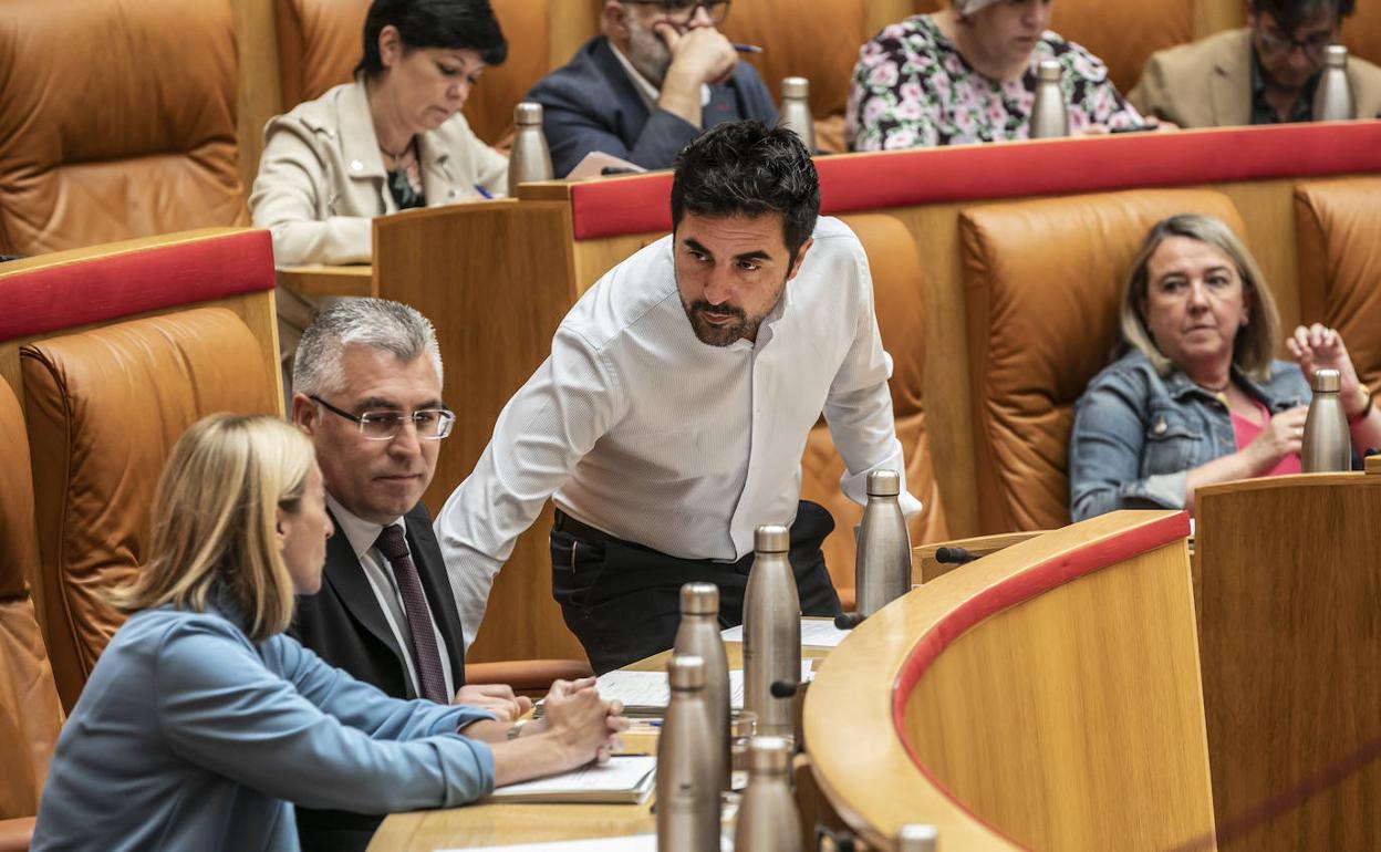 El consejero de Sostenibilidad, Álex Dorado, habla con sus compañeros en el pleno. 