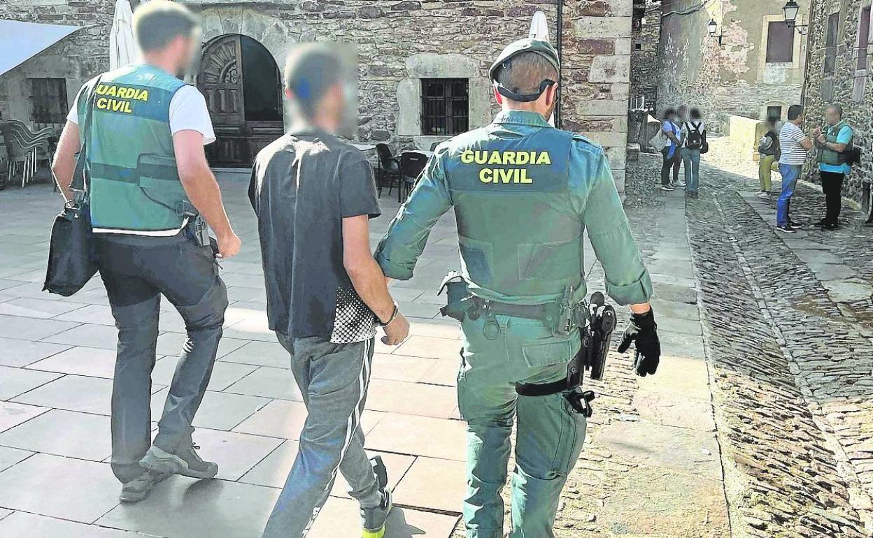 I.Z.A. es conducido, detenido y esposado, por dos agentes por las calles de Viniegra de Arriba. 