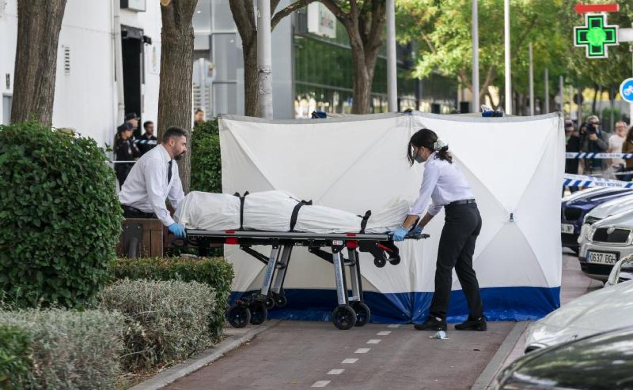 Dos trabajadores de la funeraria levantan el cadáver del joven, en las inmediaciones de la discoteca 'Caña Brava'.