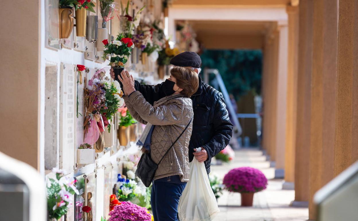 Dos personas colocan flores en el cementerio