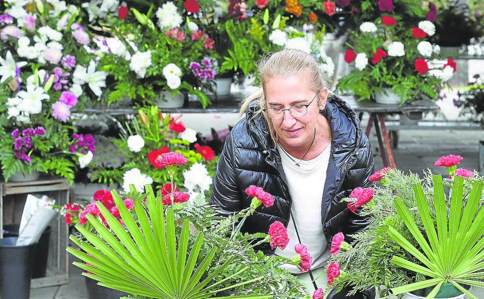 Una mujer sostiene dos centros de flores en el mercado de la plaza Joaquín Elizalde.