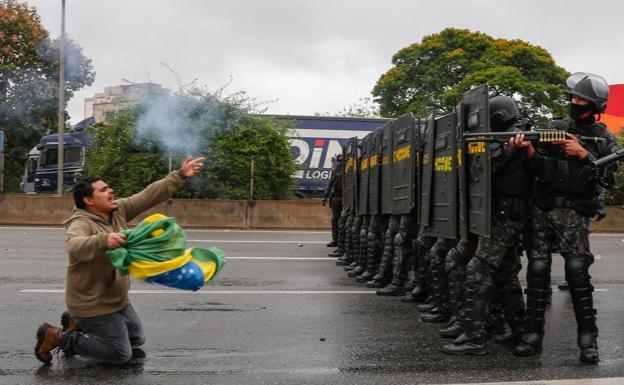 Un camionero se coloca delante de un dispositivo policial preparado para disolver el bloqueo de una autopista en Río de Janeiro.