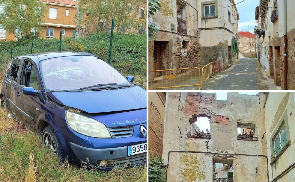 Vehículo abandonado y objeto de actos vandálicos en el camino del Molino de Alberite. A la derecha, varios edificios en ruina. 