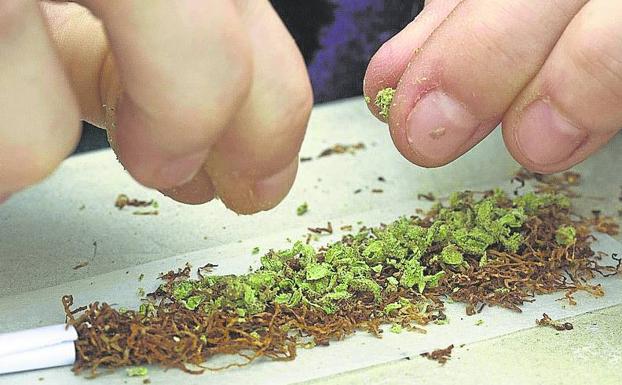 Una joven se prepara un porro de marihuana. 