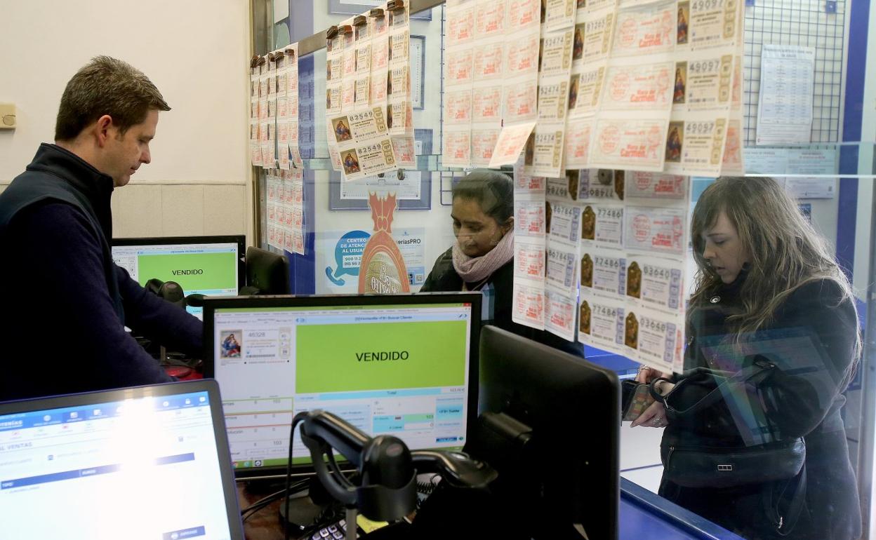 Un empleado del despacho de Muro del Carmen, que en enero vendió el primer premio del sorteo del Niño, atiende a dos mujeres. 