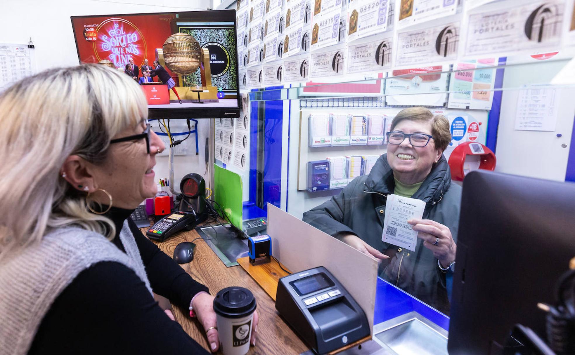 La responsable de la administración de lotería número 4 de Logroño atiende a una mujer mientras se desarrolla el sorteo navideño. 