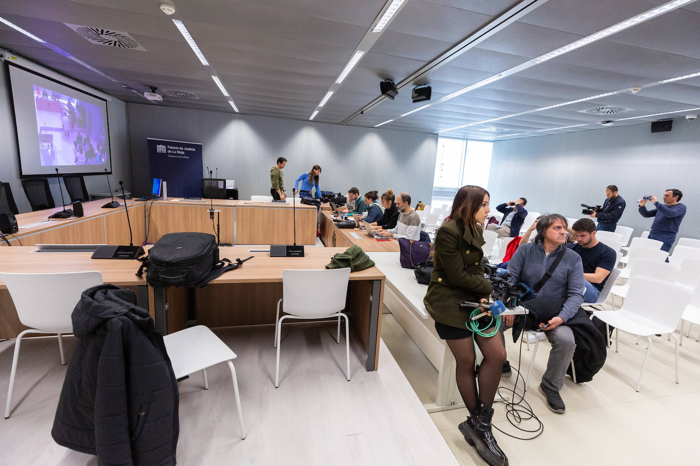 Los medios atienden a la retransmisión del juicio y toman imágenes de la pantalla.