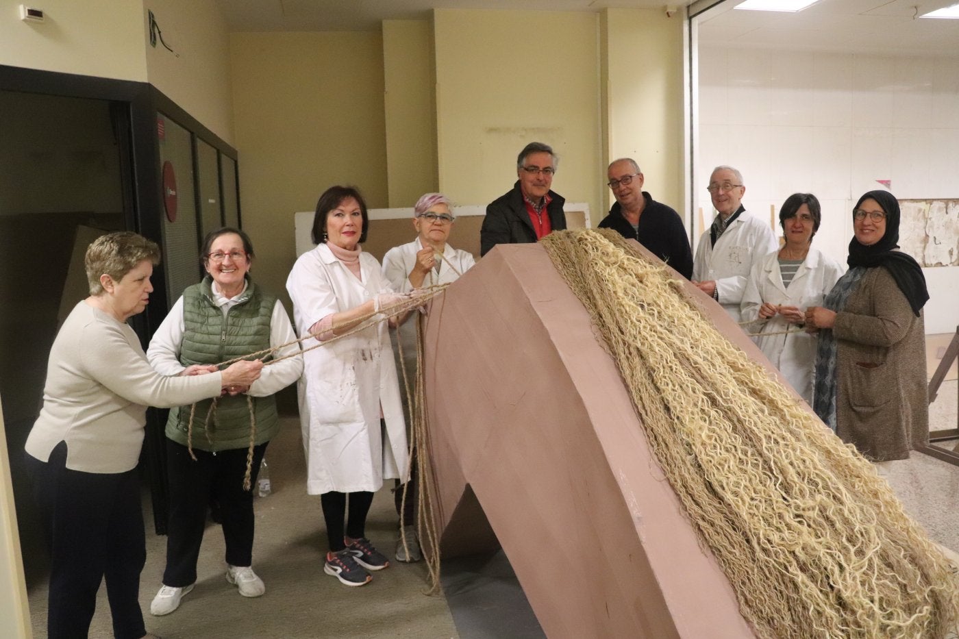 Parte del grupo de los voluntarios de la calle Tudela preparan la crin del judas del 'Caballo de Troya'.