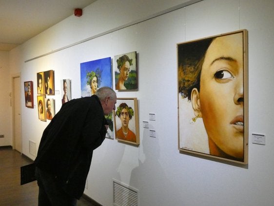 Un visitante es observado por uno de los retratos de la exposición.