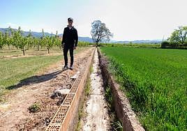 Víctor Justa, fruticultor de Albelda en una acequia seca y con los frutales al fondo.