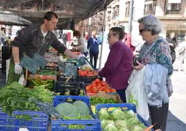 Clientas en un puesto de frutas y hortalizas, comprando ayer en el mercado de la plaza del Raso.