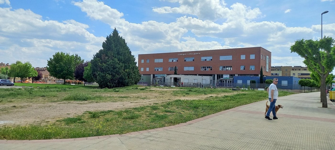 Un hombre pasea a su perro junto al solar municipal en el que se proyecta construir un nuevo parque.