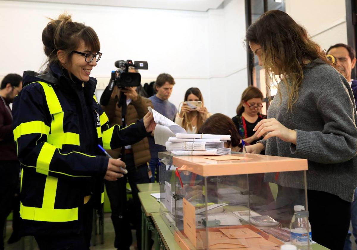 Una funcionaria de correos entrega en una mesa electoral votos enviados por correo