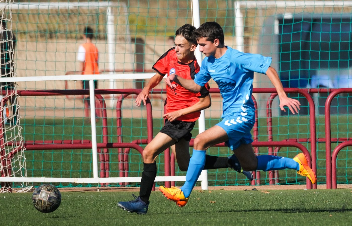 Dos jugadores cadetes corren para tratar de hacerse con el balón.