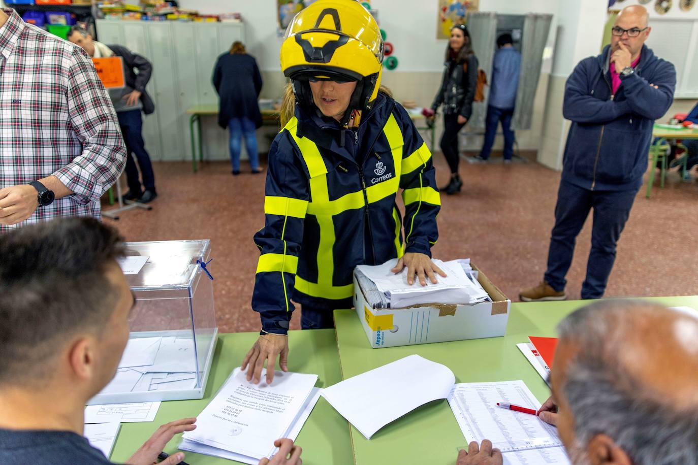 Una trabajadora Correos entrega en la mesa de un colegio electoral los votos por correo.