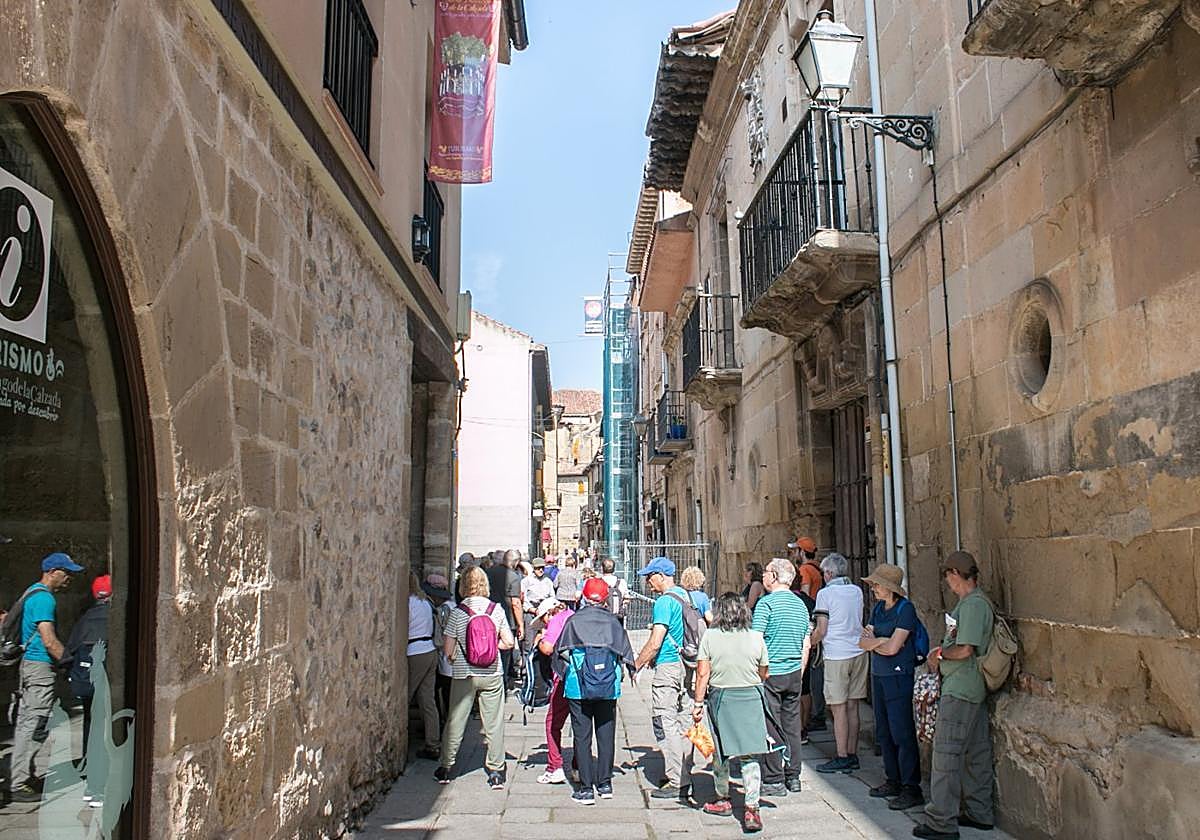 Visitantes junto a la oficina de turismo y el edificio recientemente declarado en ruina, en la calle Mayor.