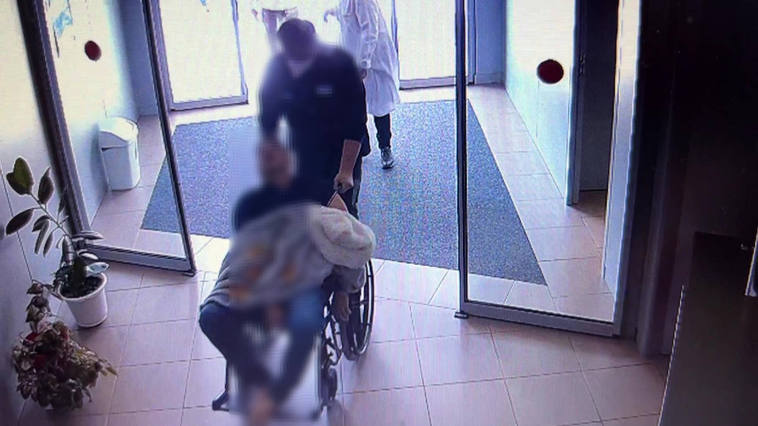 Uno de los dos detenidos, con el fallecido en silla de ruedas, en la entrada del centro de salud.