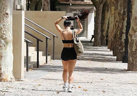 Una joven se recoge el pelo para mitigar el calor mientras camina por una calle de la capital riojana, en las horas centrales del día.