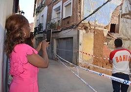 Vecinos afectados por el derrumbe observan los daños en la pared lateral del edificio de viviendas del número 18 de la calle San Andrés.