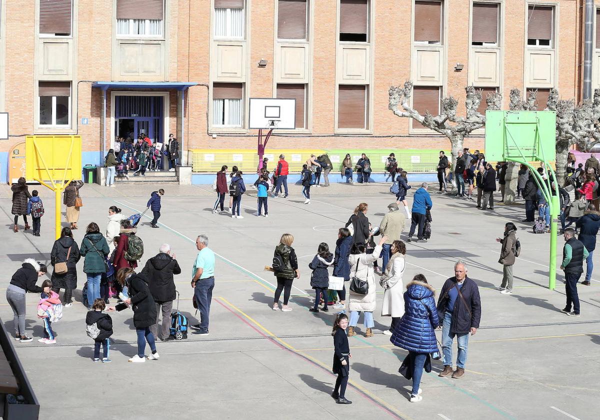 Familias y alumnos se despiden a la entrada de un colegio.