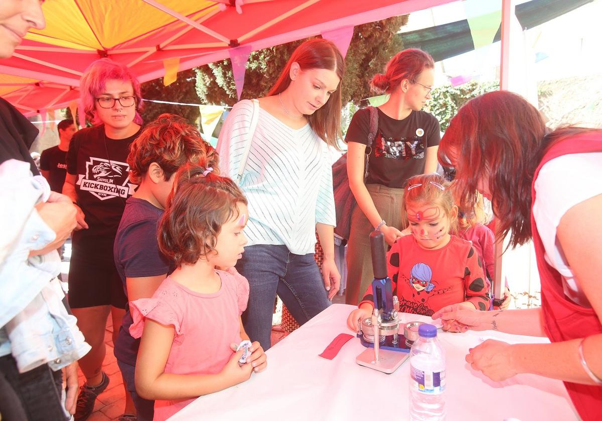 Dos niñas esperan a colocar sus dibujos en una máquina troqueladora para obtener la chapa.