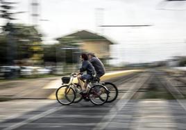 Dos personas cruzan en bici por las vías del tren que atraviesan el casco urbano de Rincón de Soto.