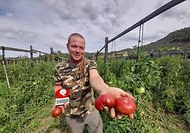 Víctor López con su último premio, sus tomates y el balneario de La Albotea al fondo.