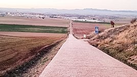 Tramo pavimentado del Camino de Santiago junto al área de descanso, a la derecha de la imagen.