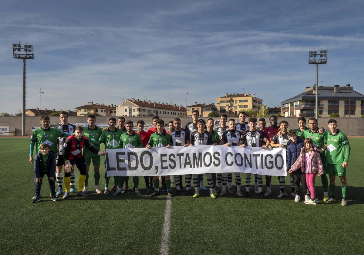 Los dos equipos, con la pancarta de apoyo a Ledo.