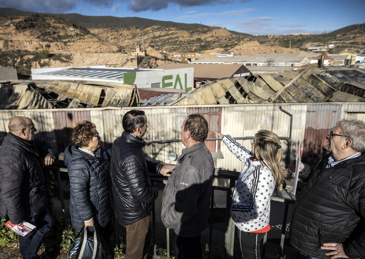 Imagen secundaria 1 - A la izquierda Antonio Guerrero, Mari Cruz Ruiz, Juan Pedro López, Juan Luis Ochoa, Rosa María Gil de Muro y Fernando Roldán observan la ruina que dejó el fuego en Calzados Fal. A la derecha después de que los bomberos abrieran huecos para atacar el fuego, el humo ya no salía este lunes de la nave.