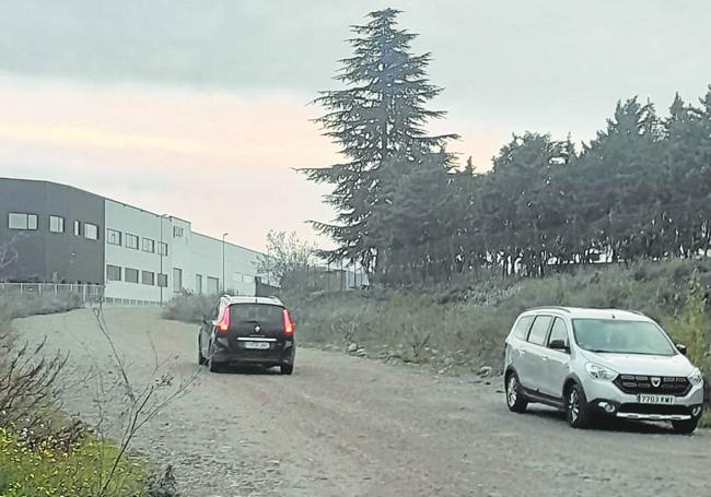 Coches circulando por el camino de acceso irregular que conecta los polígonos La Portalada y Puente Madre.