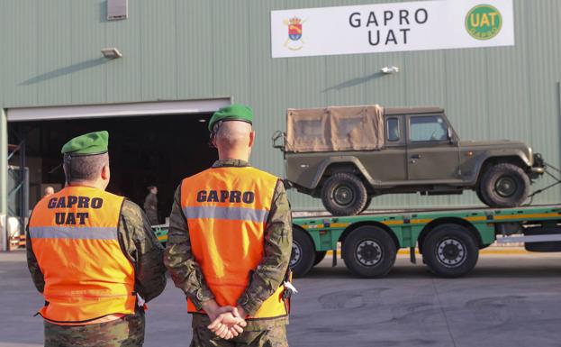 Dos soldados vigilan un remolque de transporte militar. 