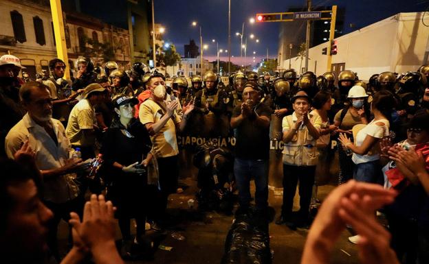 Manifestantes aplauden en honor a un fallecido en medio de los enfrentamientos que yace en el suelo 