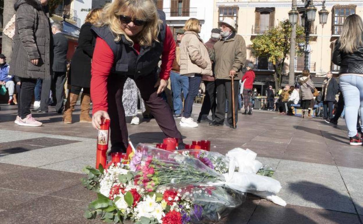 Una mujer coloca una vela en el lugar en el que falleció el sacristán de la Iglesia de La Palma.