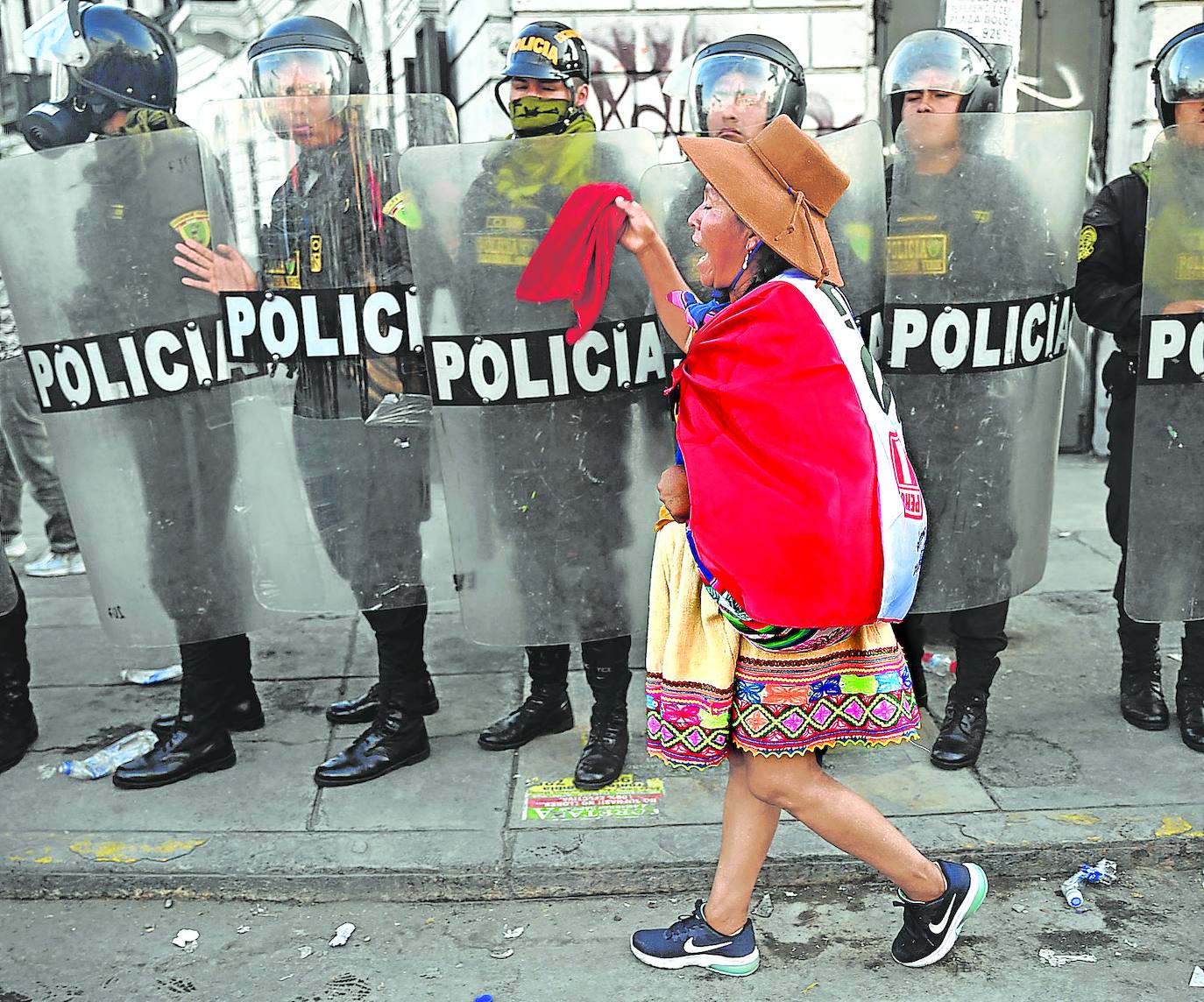 Una mujer indígena pasa ante el cordón policial durante una de las protestas de esta semana en Lima. afp