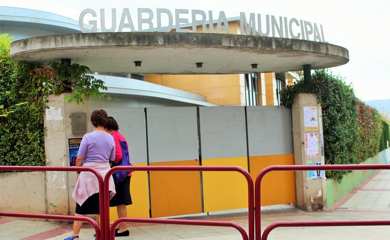 Dos mujeres observan un cartel colgado en la puerta de la guardería municipal de Villamediana de Iregua. 