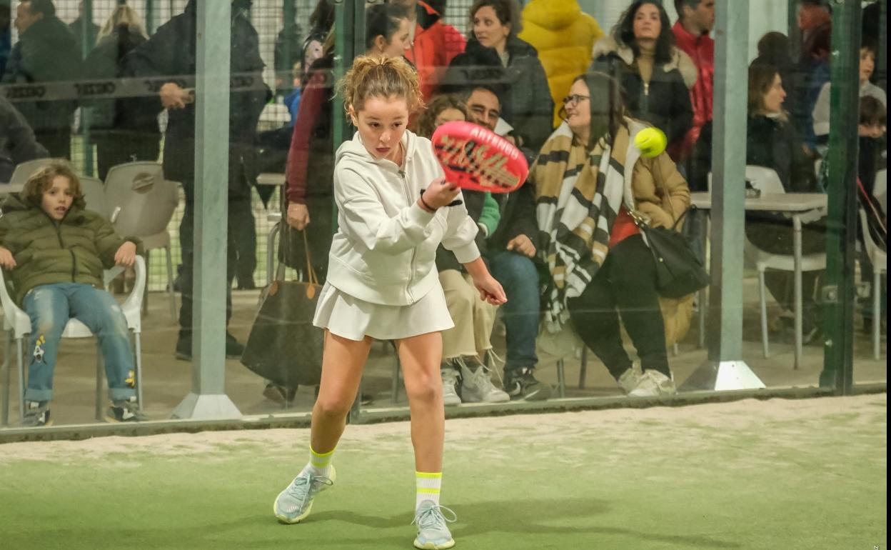 Una joven jugadora de pádel golpea la pelota con la pala durante un partido. 