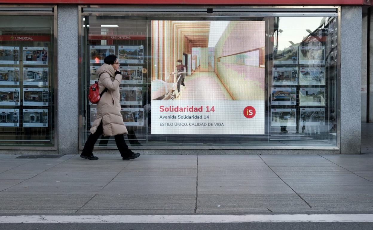 Una joven se fija en las viviendas que ofrece en su cristalera una céntrica inmobiliaria de Logroño. 