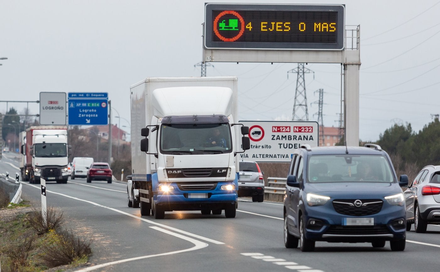 Camiones pequeños transitan a la altura de Agoncillo por la N-232, bajo el anuncio de prohibición de que los vehículos de cuatro o más ejes circulen por ella. 
