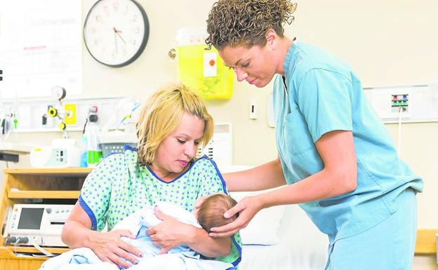 Una matrona ayuda a una madre con su recién nacido. l.